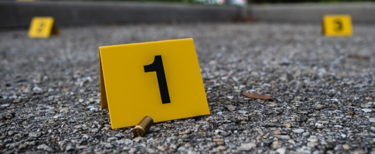 Bullet casing on the ground next to yellow crime scene marker