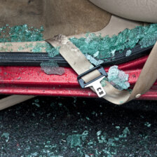 close up of car seatbelt with shattered glass in the vehicle door frame