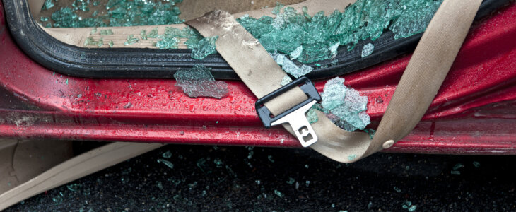 close up of car seatbelt with shattered glass in the vehicle door frame