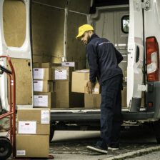 African American postal worker loading cardboard boxes